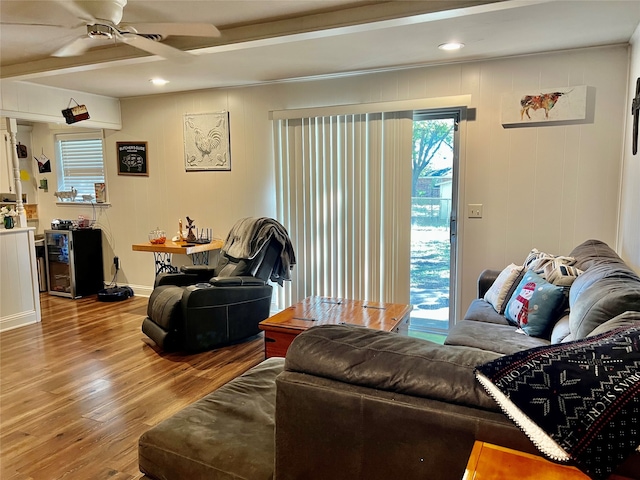 living room with hardwood / wood-style floors, ceiling fan, and beam ceiling