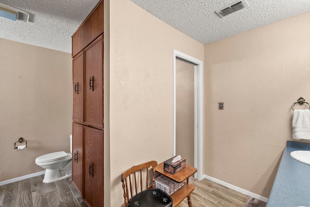 bathroom featuring wood-type flooring, a textured ceiling, toilet, and sink