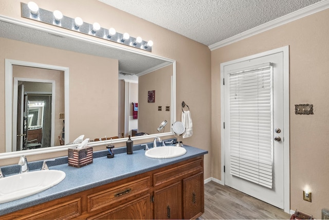 bathroom featuring vanity, wood-type flooring, a textured ceiling, and ornamental molding