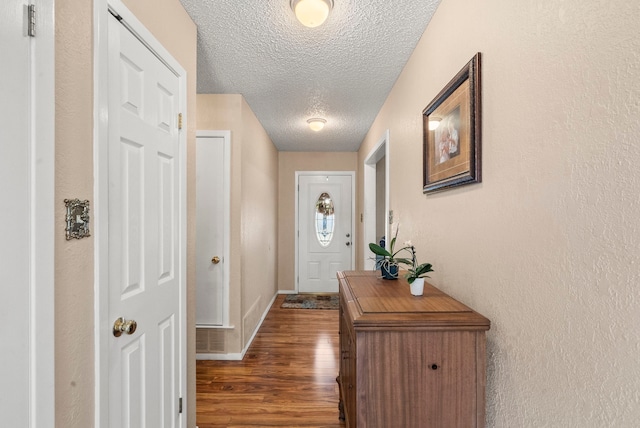 doorway to outside featuring dark wood-type flooring and a textured ceiling