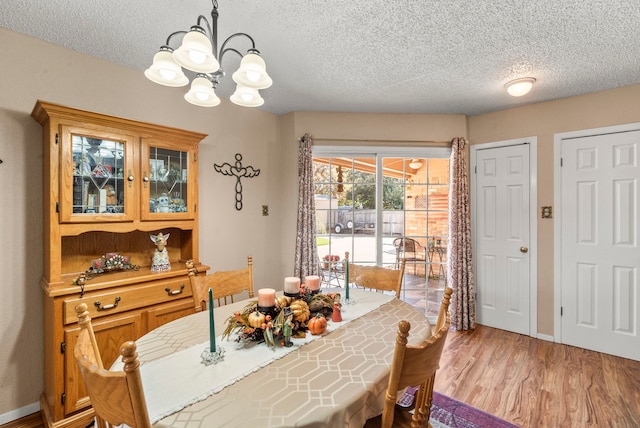 dining room with a chandelier, a textured ceiling, and light wood-type flooring