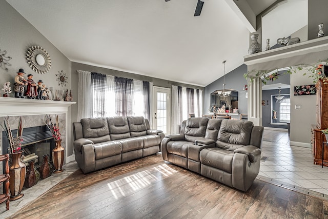 living room featuring ceiling fan with notable chandelier, vaulted ceiling, hardwood / wood-style flooring, and a fireplace