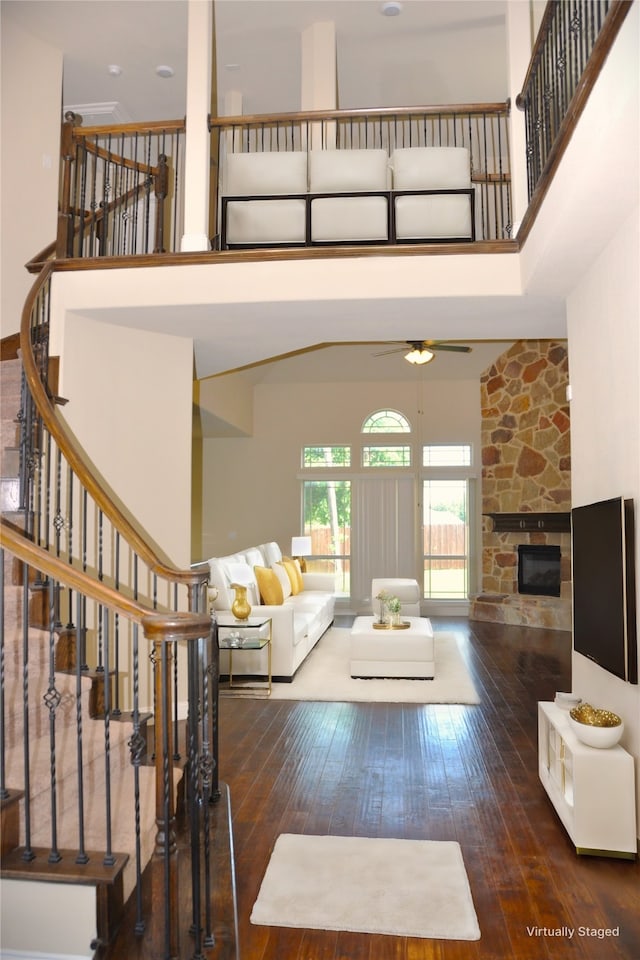 living room featuring a stone fireplace, dark hardwood / wood-style floors, and a high ceiling