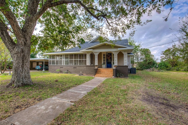 view of front facade featuring central AC unit, a sunroom, a carport, and a front lawn