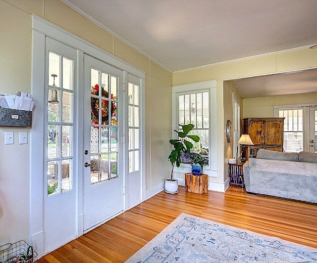 entryway with french doors, crown molding, and wood-type flooring