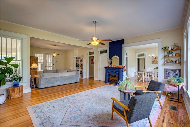 living room featuring hardwood / wood-style flooring, ceiling fan with notable chandelier, and crown molding