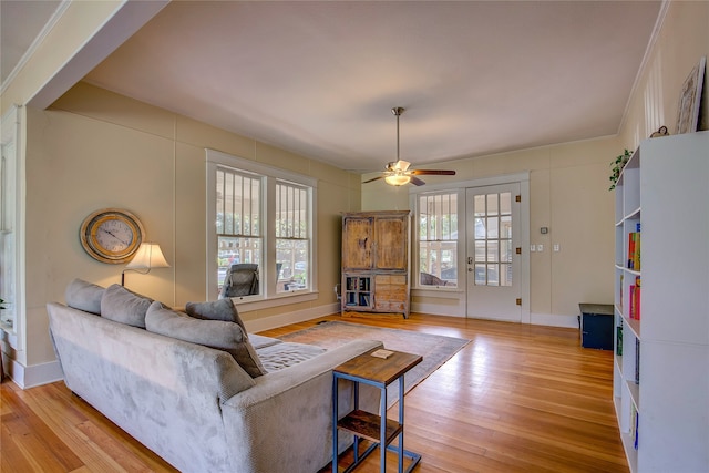 living room with ornamental molding, ceiling fan, and light hardwood / wood-style floors