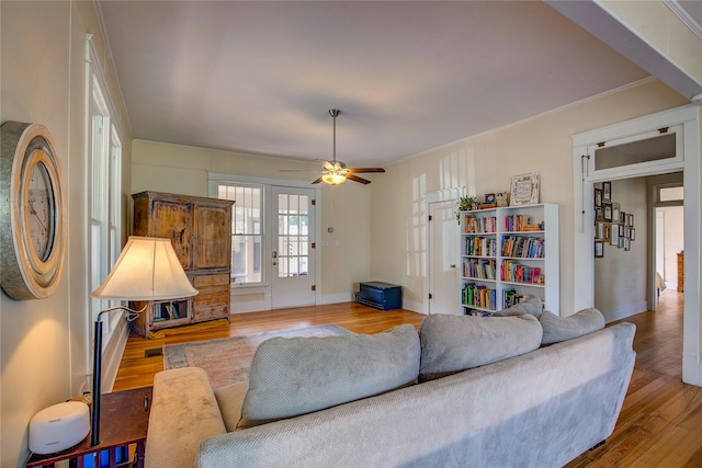 living room featuring hardwood / wood-style floors, ceiling fan, and ornamental molding