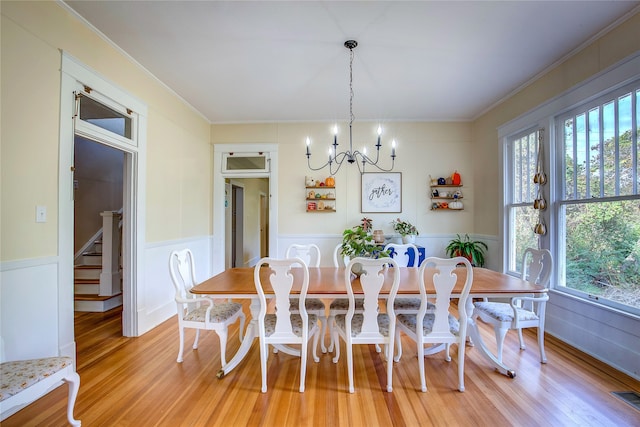 dining room with light wood-type flooring, crown molding, and a notable chandelier