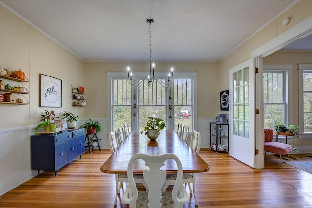 dining area with light wood-type flooring, a notable chandelier, and crown molding