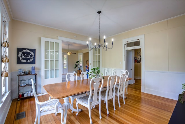 dining room featuring hardwood / wood-style flooring, ceiling fan with notable chandelier, and crown molding