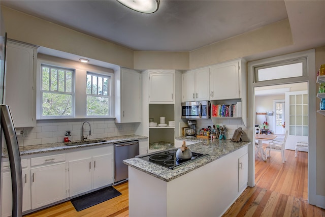 kitchen featuring white cabinets, appliances with stainless steel finishes, light hardwood / wood-style floors, and backsplash