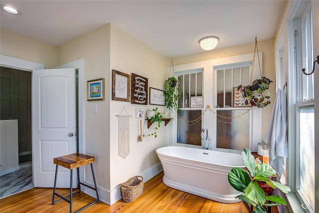 339 N 1st St, Point, TX 75472 - full bathroom featuring a freestanding tub, wood finished floors, and baseboards