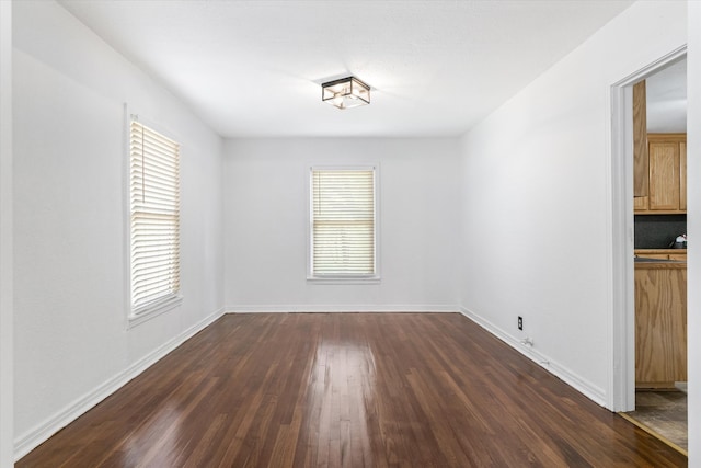 spare room with dark hardwood / wood-style flooring and a healthy amount of sunlight