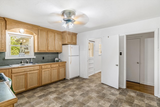 kitchen featuring ceiling fan, sink, backsplash, stove, and white fridge