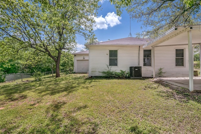 back of property with a lawn, cooling unit, and a garage