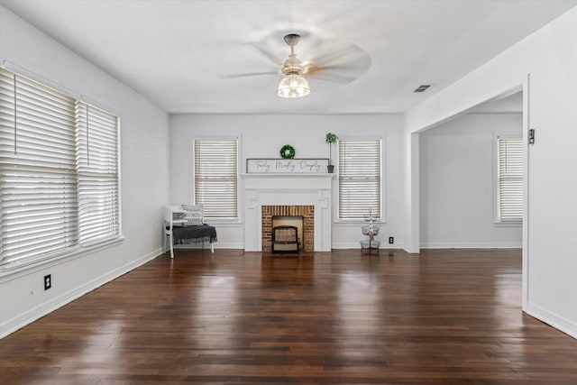 unfurnished living room with a brick fireplace, ceiling fan, and dark wood-type flooring