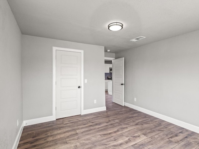 empty room featuring wood-type flooring and a textured ceiling