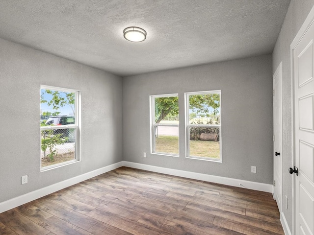 unfurnished room with dark wood-type flooring and a textured ceiling