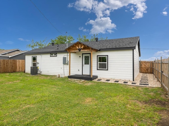 back of house with central air condition unit and a yard