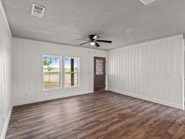 empty room with ornamental molding, dark hardwood / wood-style flooring, a textured ceiling, and ceiling fan