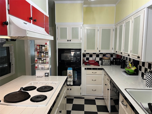 kitchen featuring white cabinetry, tile counters, black dishwasher, and hanging light fixtures