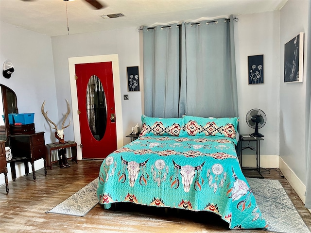 bedroom with ceiling fan, wood-type flooring, and a fireplace