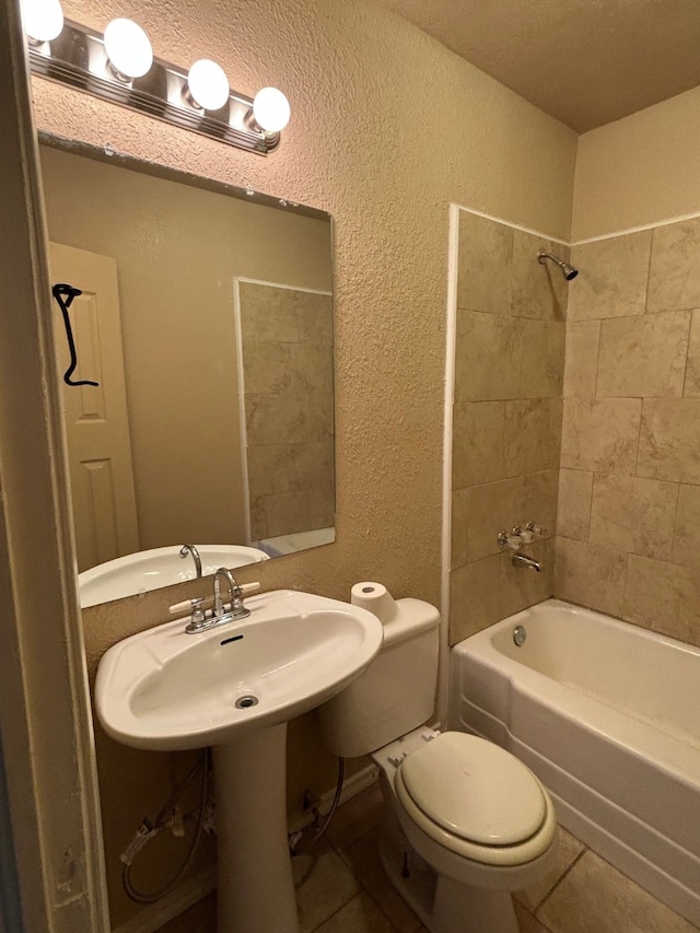 bathroom featuring a textured ceiling, tile patterned flooring, tiled shower / bath combo, and toilet