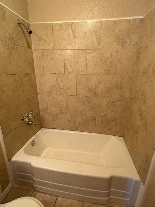 bathroom featuring toilet and tiled shower / bath