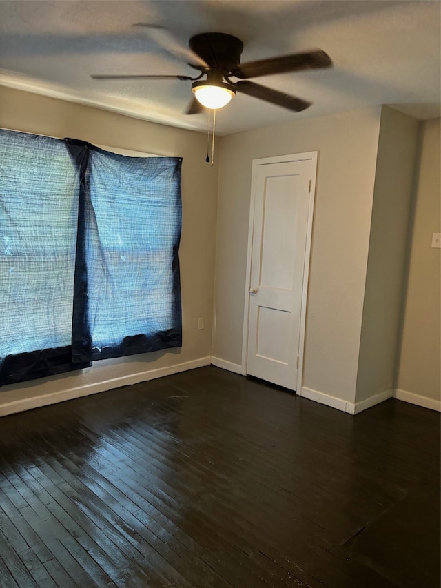 spare room with dark hardwood / wood-style flooring and ceiling fan