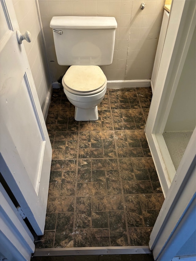 bathroom with tile walls and toilet