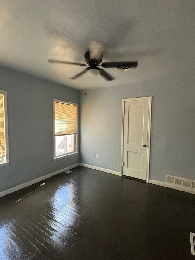 empty room with dark wood-type flooring and ceiling fan