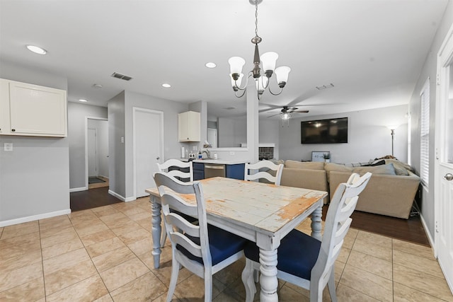 tiled dining space with ceiling fan with notable chandelier and sink