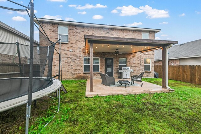 back of house with a patio, a yard, a trampoline, and ceiling fan