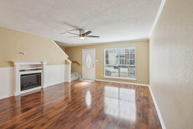 unfurnished living room with wood finished floors, a fireplace, a textured wall, and stairs