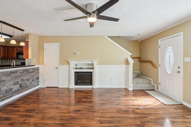 foyer featuring stairs, a wainscoted wall, a fireplace, and wood finished floors