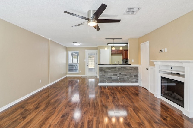 unfurnished living room with visible vents, a ceiling fan, a glass covered fireplace, dark wood-style floors, and a textured ceiling