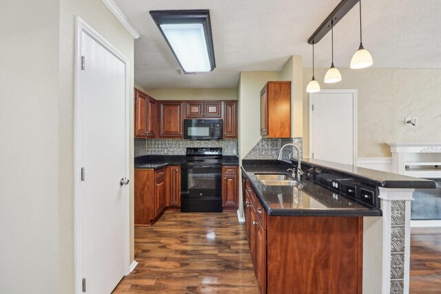 kitchen featuring decorative backsplash, dark wood-type flooring, a peninsula, black appliances, and a sink