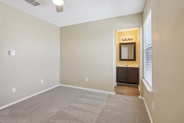 empty room featuring carpet floors, visible vents, and baseboards