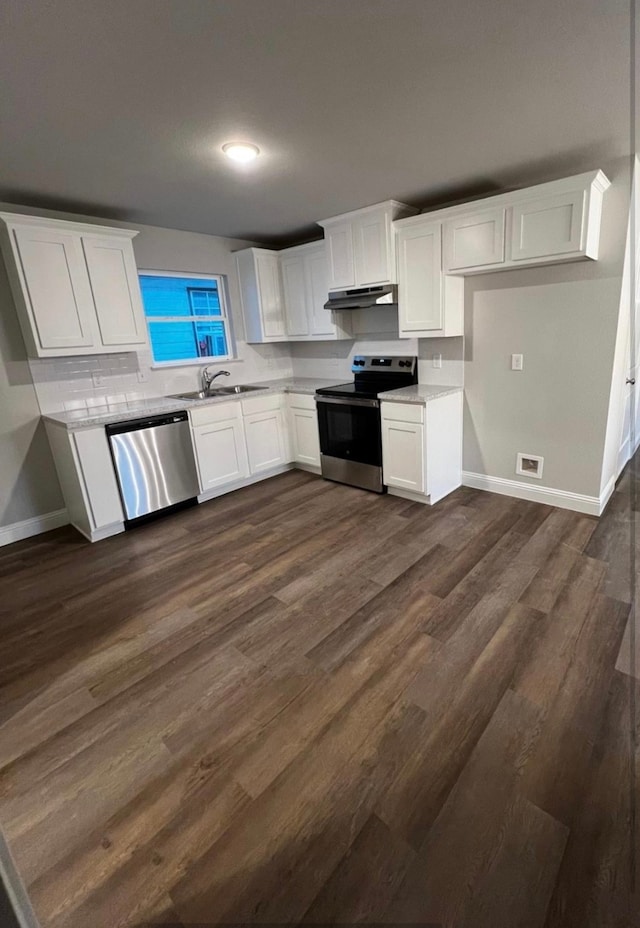 kitchen with appliances with stainless steel finishes, dark hardwood / wood-style flooring, white cabinetry, and sink