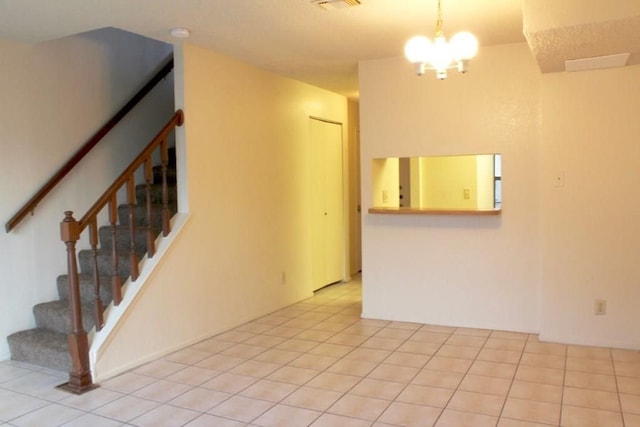 spare room with a notable chandelier and light tile patterned floors