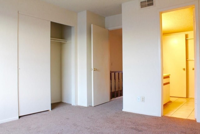 unfurnished bedroom featuring a closet and light carpet