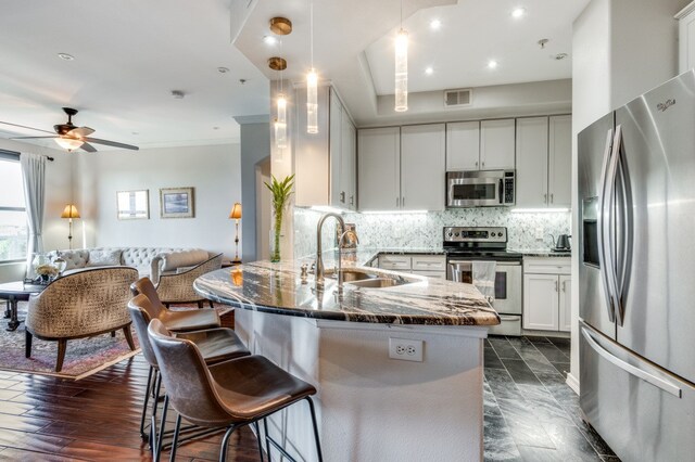 kitchen featuring stainless steel appliances, dark wood-type flooring, dark stone counters, sink, and white cabinetry