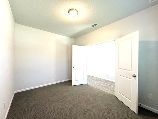 unfurnished bedroom featuring a textured ceiling and dark carpet