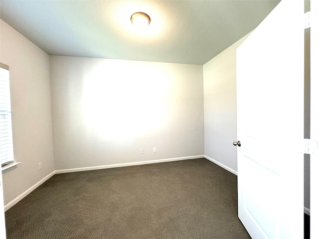 spare room featuring dark colored carpet