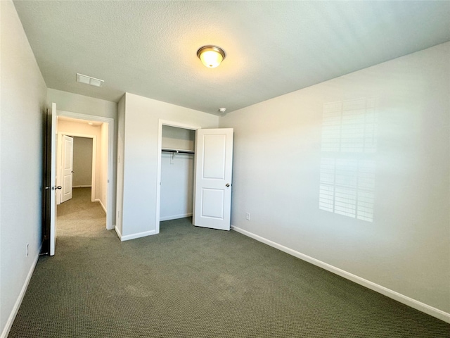 unfurnished bedroom featuring a textured ceiling, a closet, and dark carpet