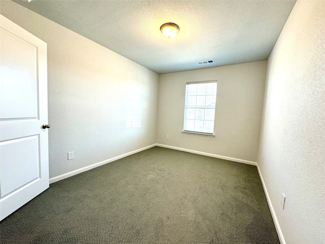 spare room featuring a textured ceiling and dark carpet