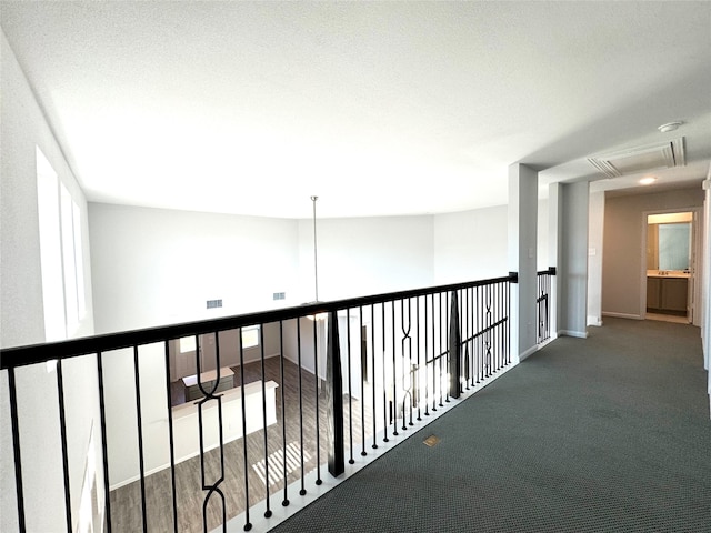 hall with dark colored carpet and a textured ceiling