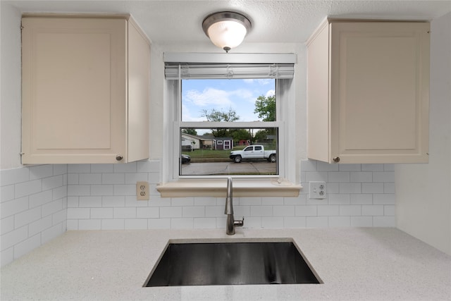 kitchen with decorative backsplash, sink, and light stone counters