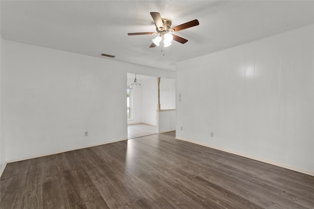 spare room featuring dark wood-type flooring, a textured ceiling, and ceiling fan with notable chandelier